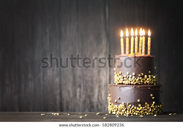 Chocolate birthday cake\
with gold candles