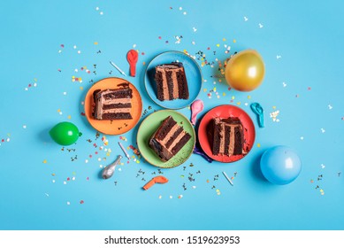 Chocolate Birthday Cake Slices On Plates, Candles, Balloons, And Confetti On A Blue Table. Above View Of Festive Dessert. New Year Celebration Concept