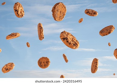 Chocolate biscuit cookies flying on a blue sky with clouds. Summer outdoor sweet food concept.  - Powered by Shutterstock