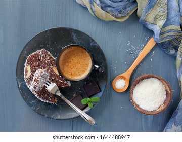 Chocolate biscuit salami with walnuts and coconut flakes on plate with a cup of coffee, top view, flat lay