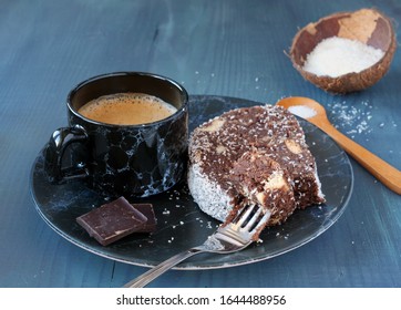 Chocolate biscuit salami with walnuts and coconut flakes with a cup of coffee on blue wooden table. Lazy cake.