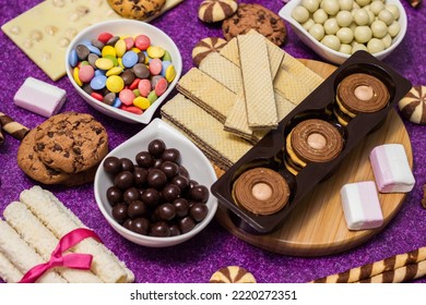 Chocolate and biscuits background. Many pieces of chocolate, candies, cookies, biscuits, cakes, donuts, and other sweets. Milk chocolate and dark chocolate, waffle coconut. Purple background - Shutterstock ID 2220272351