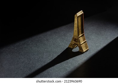 Chocolate Bonbon In The Shape Of A Golden Eiffel Tower. Plain Black Background