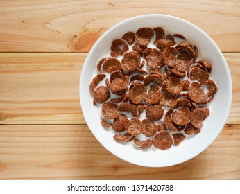 Chocolate breakfast cereal in a white bowl on wooden table with copy space. Top view. Healthy breakfast concept. - Powered by Shutterstock