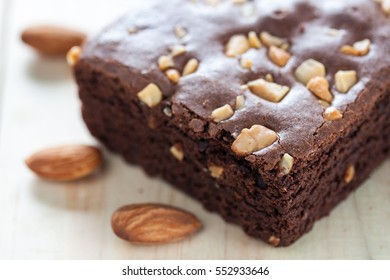 Chocolate brownie with almond topping over wooden background