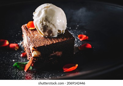 Chocolate Brownie Cake With Vanilla Ice Cream On Black Plate