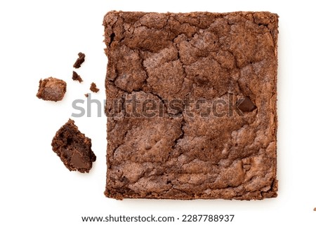 Chocolate brownie with chocolate chips next to crumbs isolated on white. Top view.