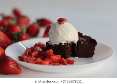 Chocolate brownie with fresh strawberries and a scoop of creamy vanilla ice cream, perfect for dessert menus and sweet cravings. Featuring Egg less preparation of brownie. Shot on white background