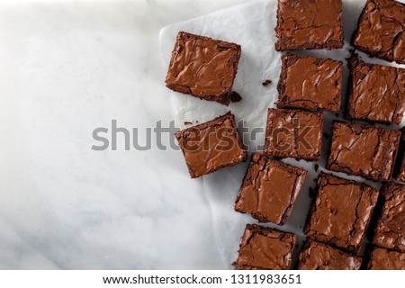 Chocolate brownie on paper on white marble top view flat lay looking down with text space on left copy space