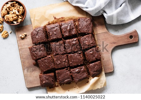 Chocolate brownie squares with walnuts on cutting board, top view, horizontal composition. Flat lay food
