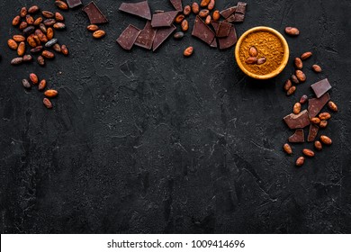 Chocolate And Cacao Concept. Cocoa Powder In Bowl Near Cocoa Beans And Broken Chocolate On Black Background Top View Copy Space