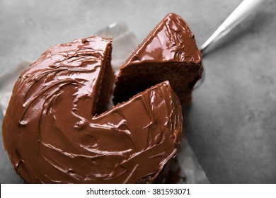 Шоколадный торт с отрезанным куском и лезвием на сером фоне, крупный план