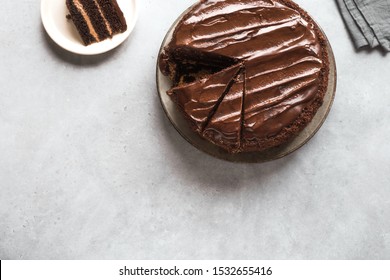 Chocolate Cake With Cut Pieces On Light Gray Background, Top View, Copy Space. Classic Chocolate Cake With Dark Chocolate Ganache.