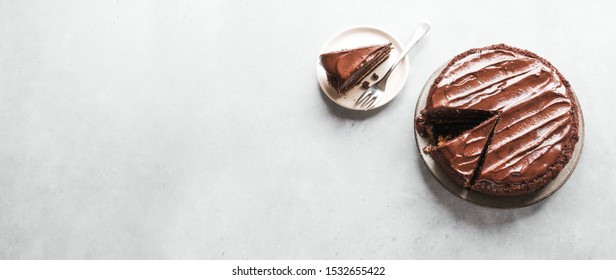 Chocolate Cake With Cut Pieces On Light Gray Background, Top View, Copy Space. Classic Chocolate Cake With Dark Chocolate Ganache.