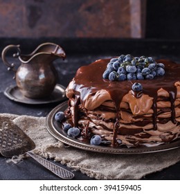 Chocolate cake from chocolate pancakes with icing, with blueberries.Vintage style.selective focus. - Shutterstock ID 394159405
