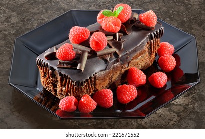 Chocolate Cake With Raspberries On Black Octagonal Plate.