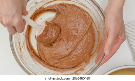 Chocolate cake recipe. Mixing cake batter in a glass bowl. Close up baking process, flat lay