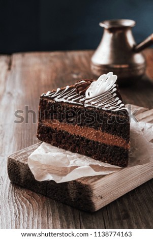 Chocolate cake side view on a cutting board rustic on a wooden table.