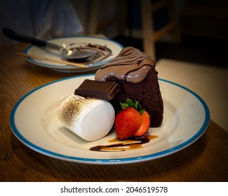Chocolate cake with a sliced strawberry, a giant marshmallow, and a piece of chocolate for dessert. - Shutterstock ID 2046519578