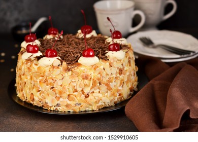 Chocolate Cake With Vanilla Cream, Cherry And Almonds On A Dark Background.
