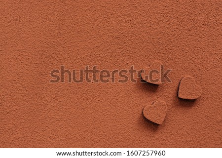 Chocolate candies heart sprinkled with cocoa powder. Abstract background.Valentines day. Cocoa texture. View from above