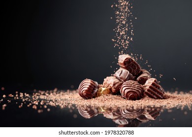 Chocolate candies on a black background sprinkled with chocolate chips. 