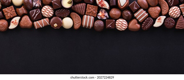 chocolate candies on blackboard background, various pralines and truffles with empty space