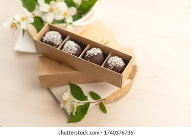 Chocolate candies in the shape of a handmade ball in a craft box on a light background decorated with jasmine flowers