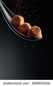 Chocolate Candy Truffle And Flying Cocoa Powder On A Dark Background. Copy Space.