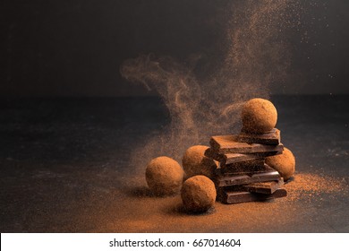 Chocolate Candy Truffle With Chocolate Pieces And Flying Cocoa Powder On A Dark Background