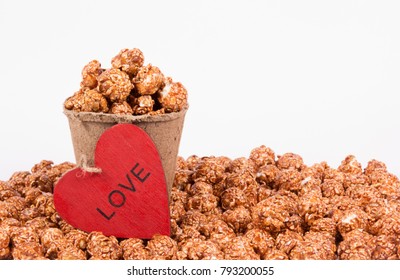 Chocolate caramel popcorn in paper bucket on white background. Popcorn and red heart. Romantic concept. St. Valentine's Day.