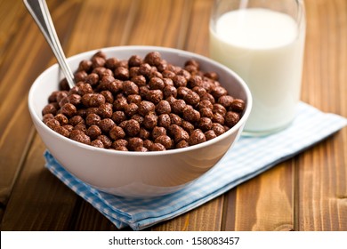 chocolate cereals in bowl and milk on wooden table