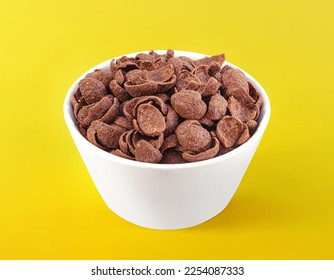 Chocolate cereals in white bowl. Chocolate flavored corn flakes. Wheat. Cocoa. Crispy. Crunchy. Breakfast. Snack. Granola. Oat.