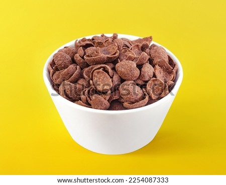 Chocolate cereals in white bowl. Chocolate flavored corn flakes. Wheat. Cocoa. Crispy. Crunchy. Breakfast. Snack. Granola. Oat.