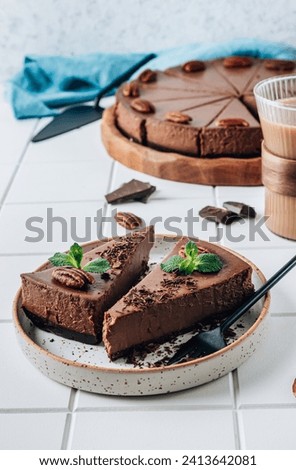 Chocolate cheesecake with pecans and mint, coffee cup on white background. Selective focus