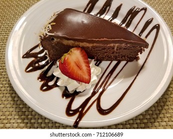 Chocolate Cheesecake Slice With Strawberry And Whipped Cream Dollop On White Plate