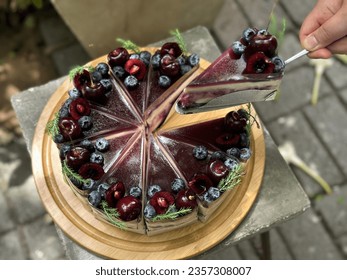 Chocolate Cherry Cake on wooden plate green background. Cropped hands of women holding Chocolate Cherry Cake on wooden plate. Hand holding chocolate cake slice. Free space for text menu coffee shop. - Powered by Shutterstock