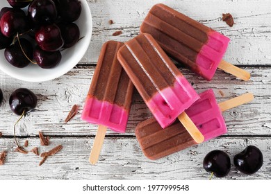 Chocolate And Cherry Ice Pops. Overhead View Table Scene On A Rustic White Wood Background.