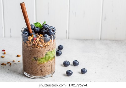 Chocolate chia pudding with fruits, granola and berries in a glass.