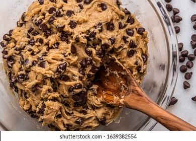 Chocolate Chip Cookie Batter in a bowl with a wooden spoon, with spilled chocolate chips - Powered by Shutterstock
