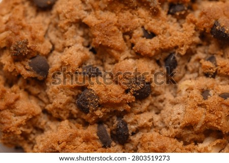 Chocolate chip cookie close-up view, in unspecified, with chocolate chips, cookie dough, with baked cookie dough, chocolate chips texture, from a top-down perspective perspective, clear detail.