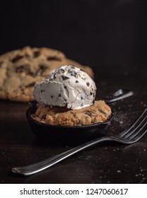 Chocolate Chip Cookie With Ice Cream On Top Baked In Cast Iron Skillet With Blurred Background