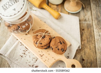 Chocolate chip cookies with milk in bottle on rustic background