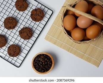 chocolate chip cookies on cooling rack with coffee beans in bamboo bowl and egg basket - Powered by Shutterstock