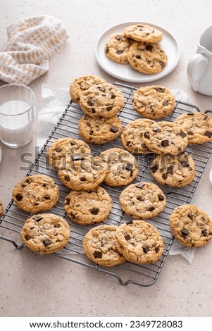 Chocolate chip cookies on a cooling rack with flaky salt served with cold milk