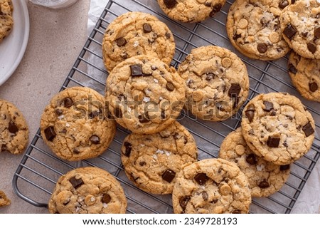Chocolate chip cookies on a cooling rack with flaky salt served with cold milk overhead shot