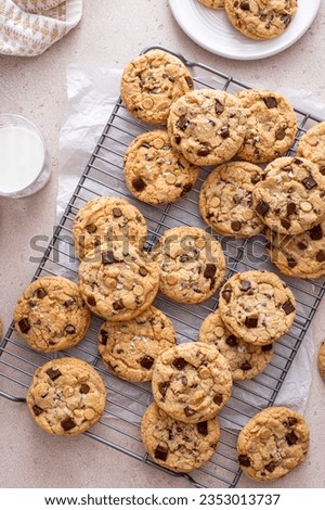 Chocolate chip cookies on a cooling rack with flaky salt served with cold milk overhead shot