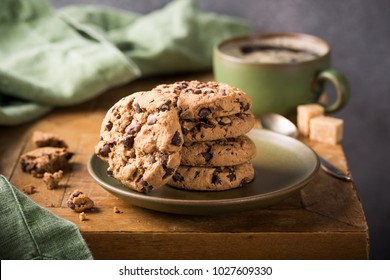 Biscotti al cioccolato su piatto verde con tazza di caffè su vecchio tavolo di legno. Messa a fuoco selettiva.