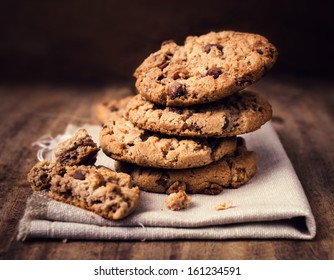 Chocolate chip cookies on linen napkin on wooden table. Stacked chocolate chip cookies close up.
