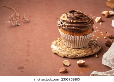 Chocolate chip muffins decorated with chocolate ganache and hazelnut on a kitchen countertop. - Shutterstock ID 2305968805